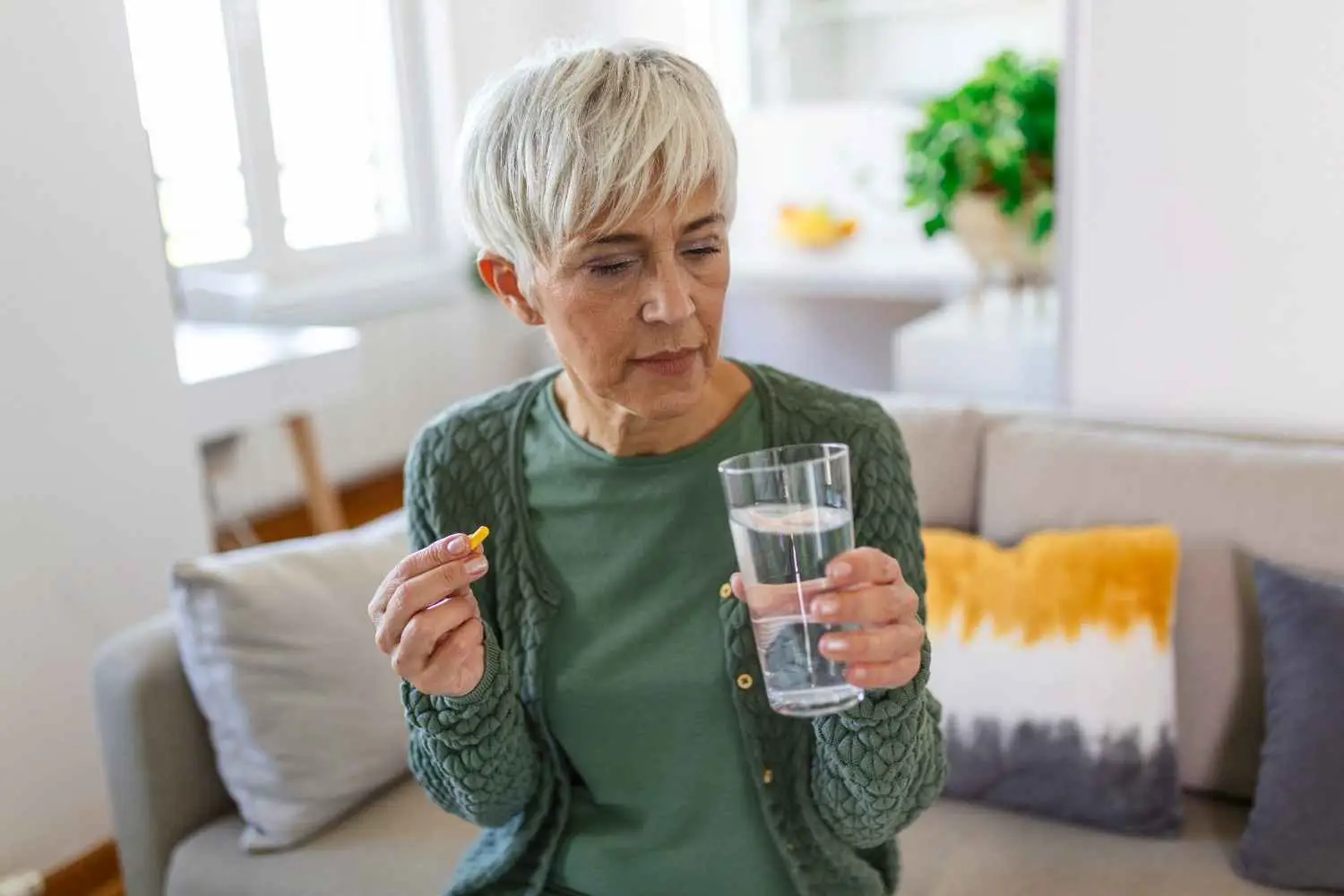 A woman taking her daily medicine with a glass of water
