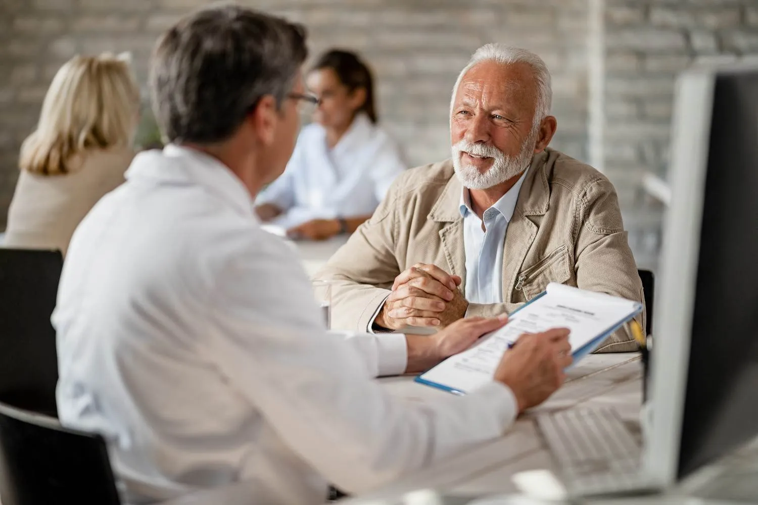 An older man going through his coverage notes with a doctor